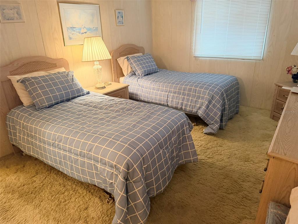 A bedroom features two twin beds with blue grid-patterned bedding and light wood paneling — 3301 ALT 19 UNIT 267, DUNEDIN, FL