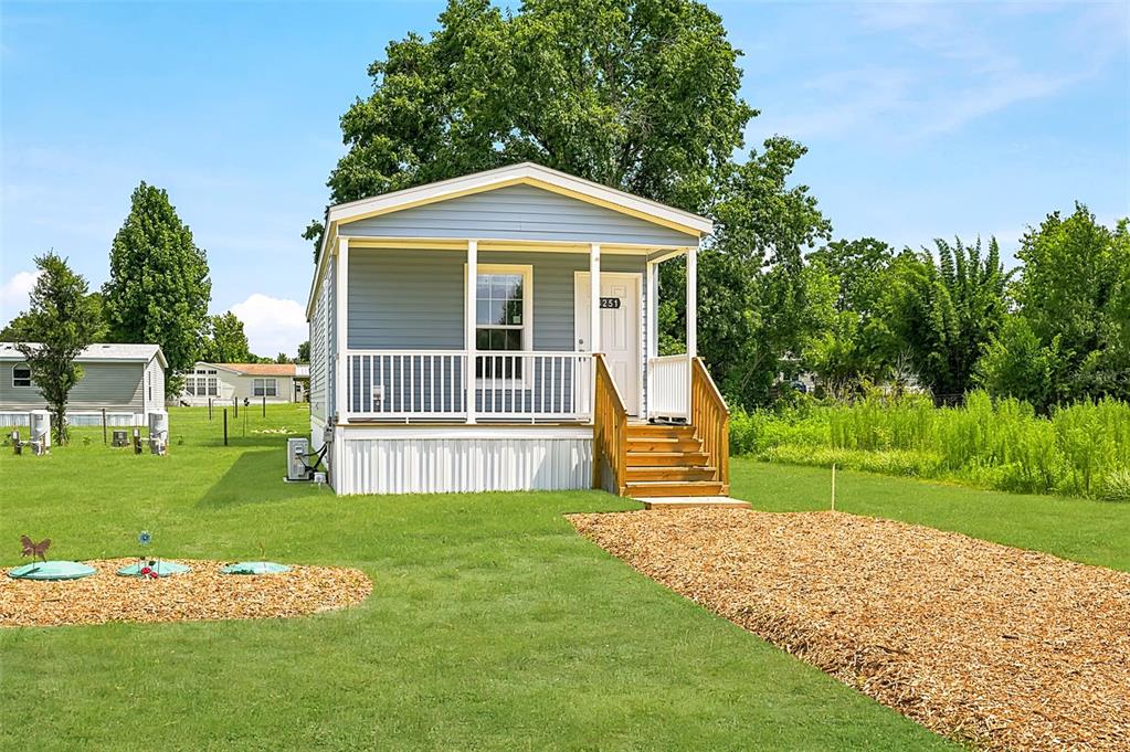 A light blue manufactured home with a front porch stands on a grassy lot — 4251 E HAWAII LANE, HERNANDO, FL