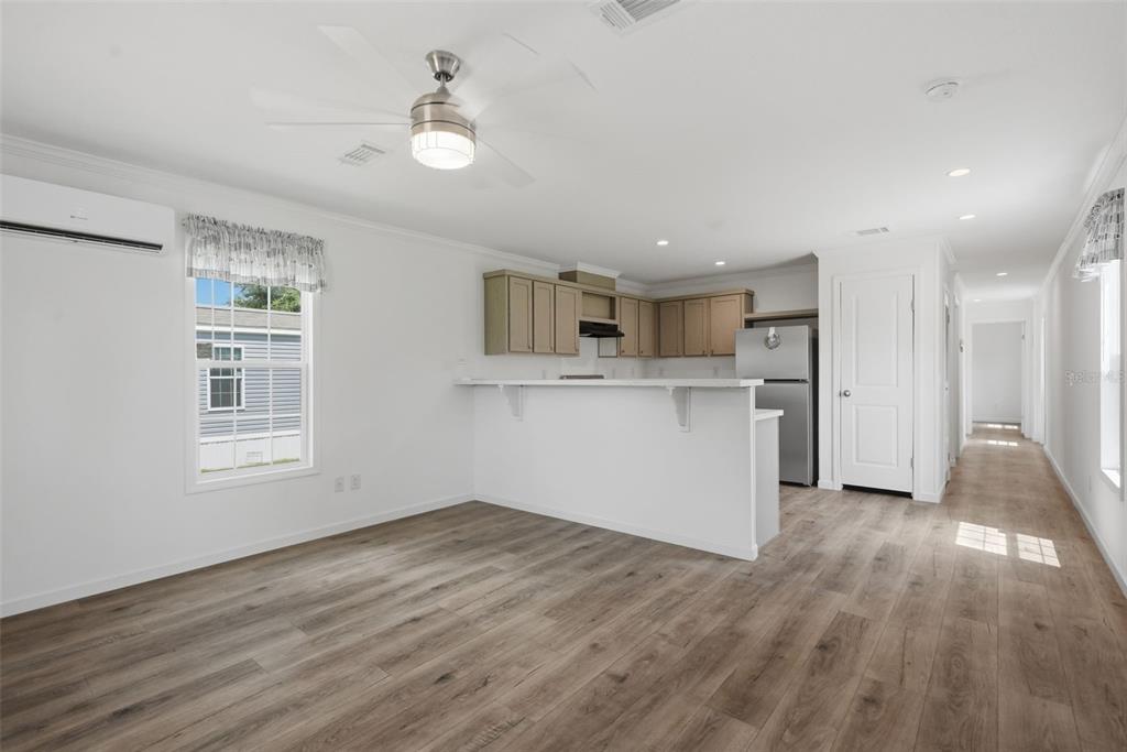 An open-concept kitchen and living area features light wood-look flooring and a breakfast bar — 4251 E HAWAII LANE, HERNANDO, FL