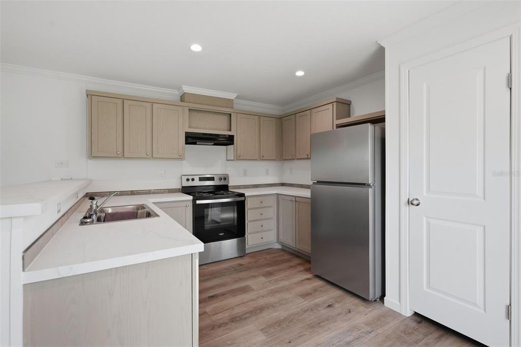 A kitchen features light wood cabinets, stainless steel appliances, and white countertops — 4251 E HAWAII LANE, HERNANDO, FL