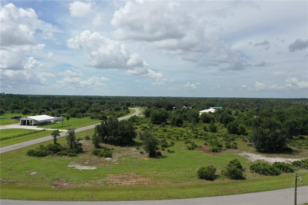 An aerial view shows a rural landscape with a paved road, trees, and a building — 40710 11TH AVENUE E, MYAKKA CITY, FL