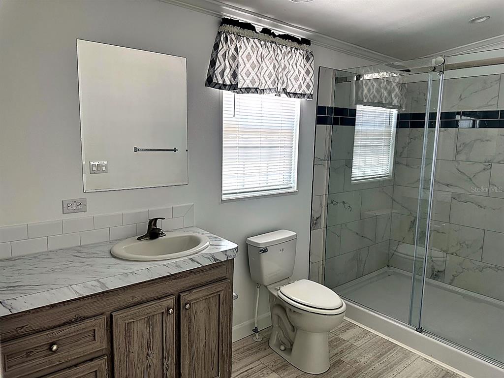 A living room with light wood-look flooring, white walls, and a front door with glass — 3492 GREENBLUFF ROAD UNIT 1119, ZELLWOOD, FL