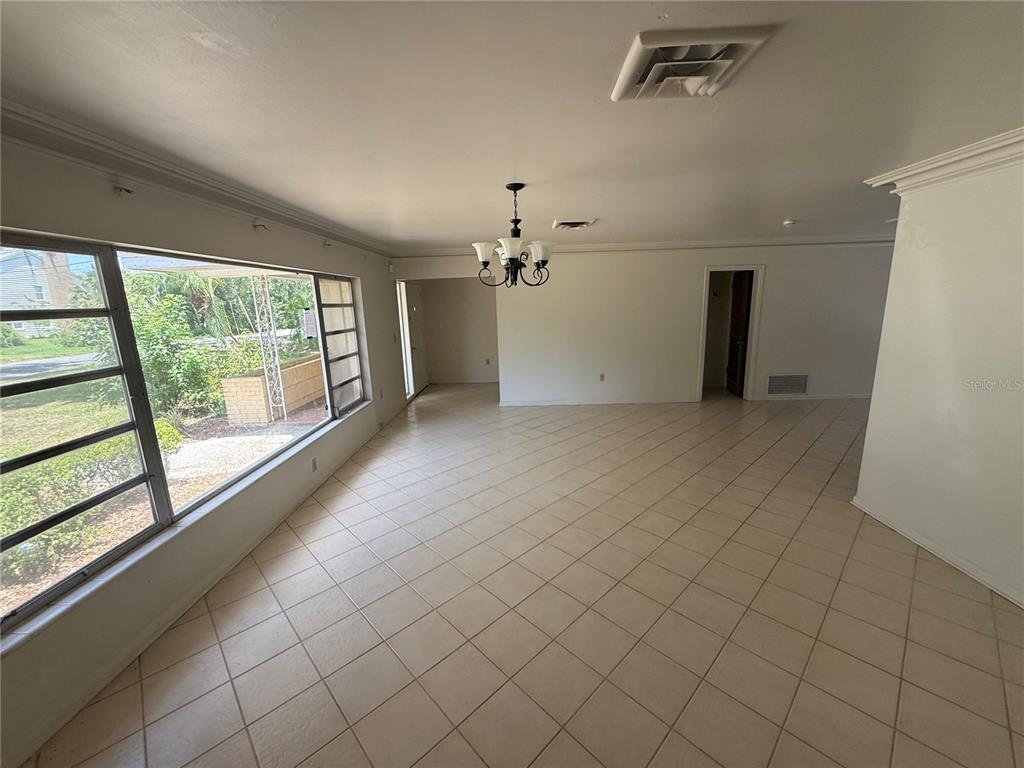 A bright, tiled dining room features a large window, a chandelier, and white walls — 1015 E MANN ROAD, BARTOW, FL