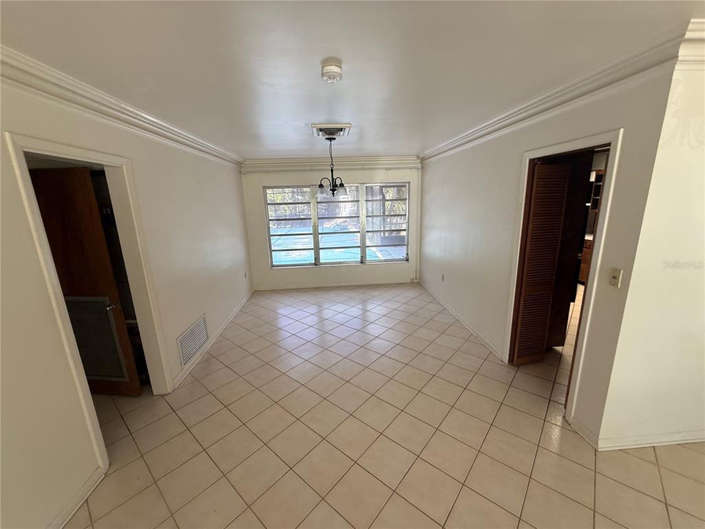 A dining room with white walls, tiled floors, a chandelier, and a view of a pool — 1015 E MANN ROAD, BARTOW, FL