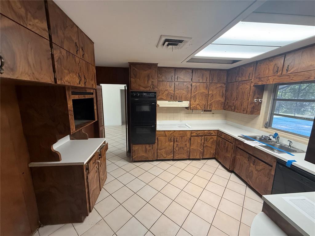 A kitchen features wood-grain cabinets, white countertops, a double wall oven, and tiled flooring — 1015 E MANN ROAD, BARTOW, FL