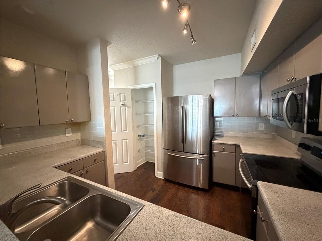 An open-concept living and dining area features hardwood floors, a staircase, and a kitchen pass-through — 204 SOUTH STREET UNIT 1053, ORLANDO, FL
