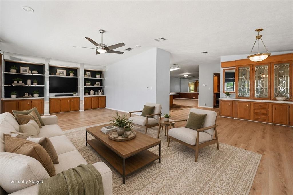 A living room with light wood floors, built-in cabinetry, and two armchairs facing a sofa — 9178 ADMIRAL STREET, BROOKSVILLE, FL