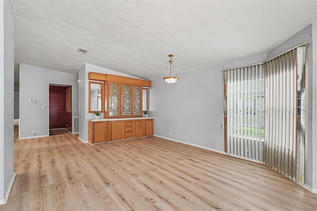 A dining room with light wood flooring, a built-in wooden hutch, and vertical window blinds — 9178 ADMIRAL STREET, BROOKSVILLE, FL
