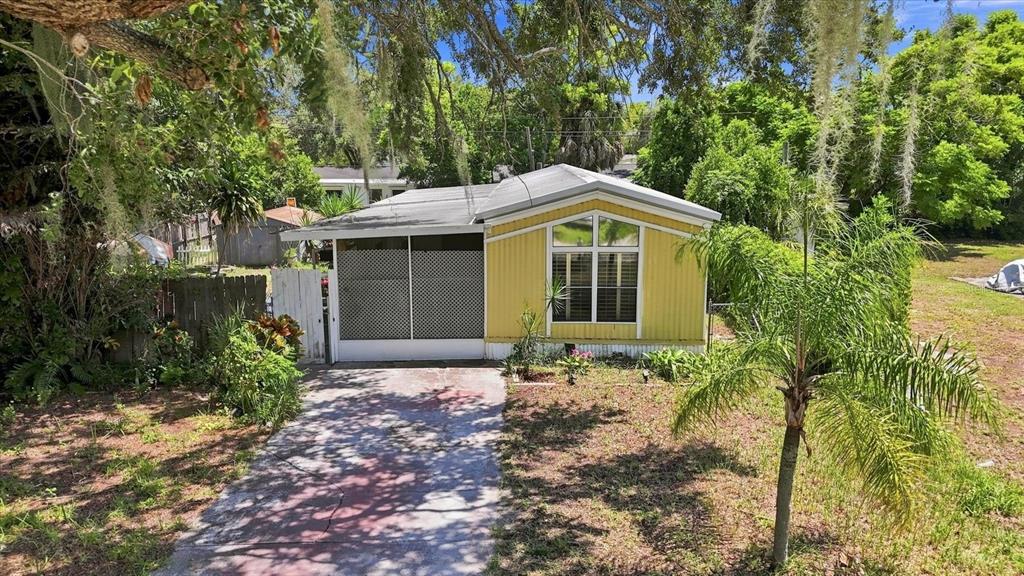 A yellow mobile home with a screened-in porch sits on a lot with mature trees — 8844 MIKE STREET, PORT RICHEY, FL
