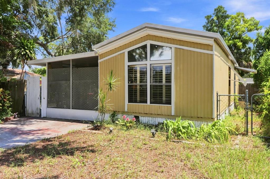 A yellow mobile home with a screened-in porch and a front yard with grass — 8844 MIKE STREET, PORT RICHEY, FL