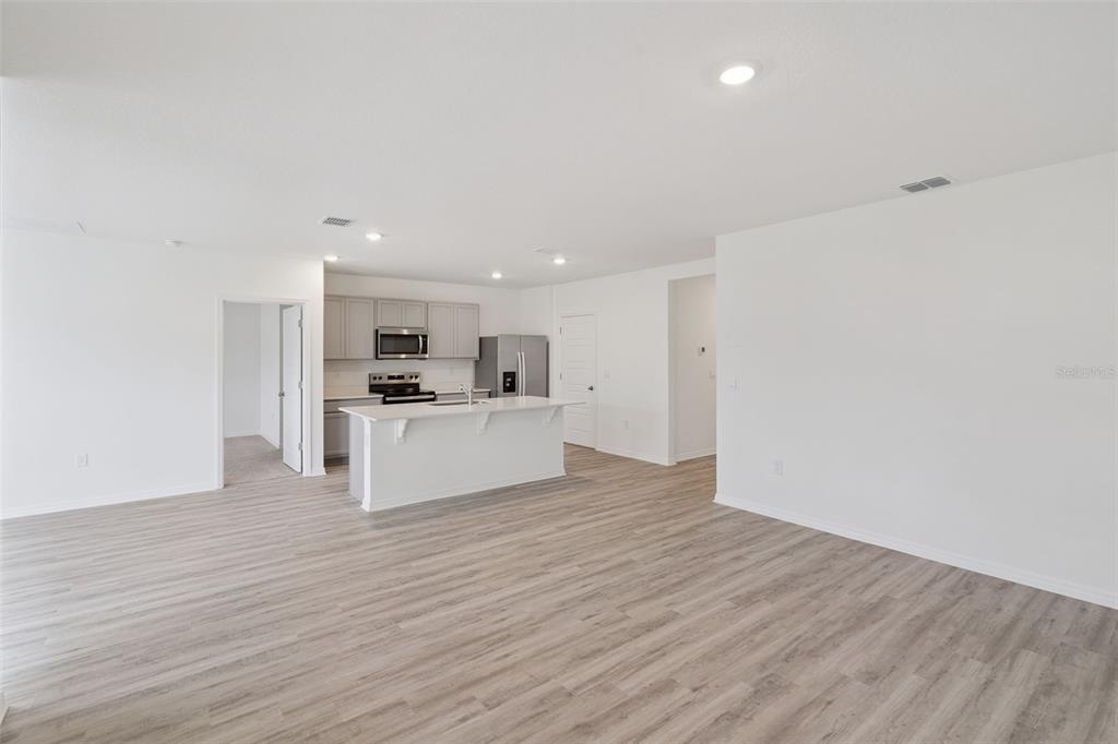 An open-concept kitchen with a white island and light wood-look flooring in a living area — 3537 RODEN ROAD, HAINES CITY, FL