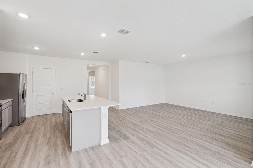 A kitchen with a center island and stainless steel refrigerator opens to a large living area — 3537 RODEN ROAD, HAINES CITY, FL