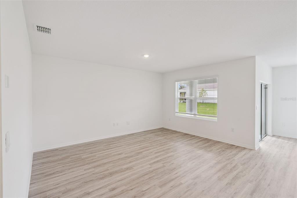 An empty room with white walls, light wood-look flooring, a window, and a sliding door — 3537 RODEN ROAD, HAINES CITY, FL