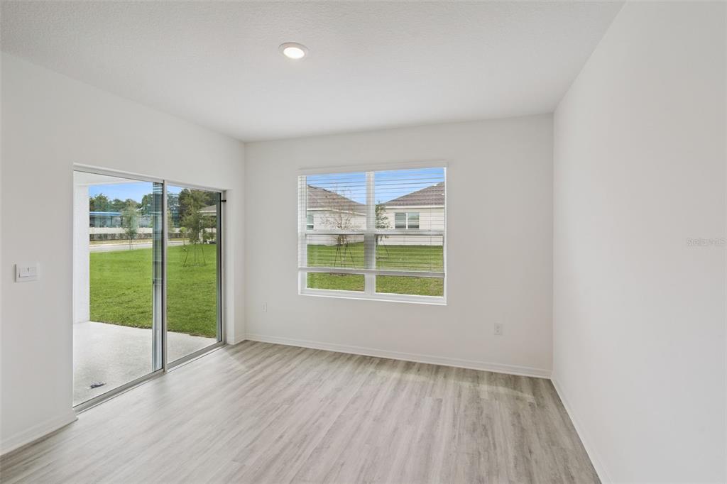 An empty room with light wood-look flooring, a sliding glass door, and a single window — 3537 RODEN ROAD, HAINES CITY, FL