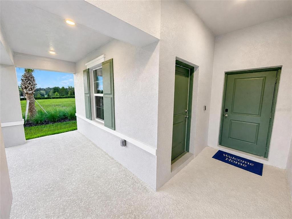 A covered porch features a green front door, a side door, and a window with shutters — 187 PUMA LOOP, GROVELAND, FL