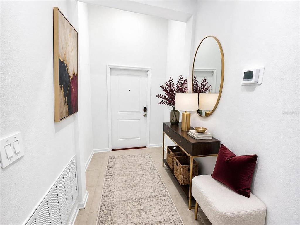A bright entryway features a console table, an oval mirror, and a white front door — 187 PUMA LOOP, GROVELAND, FL