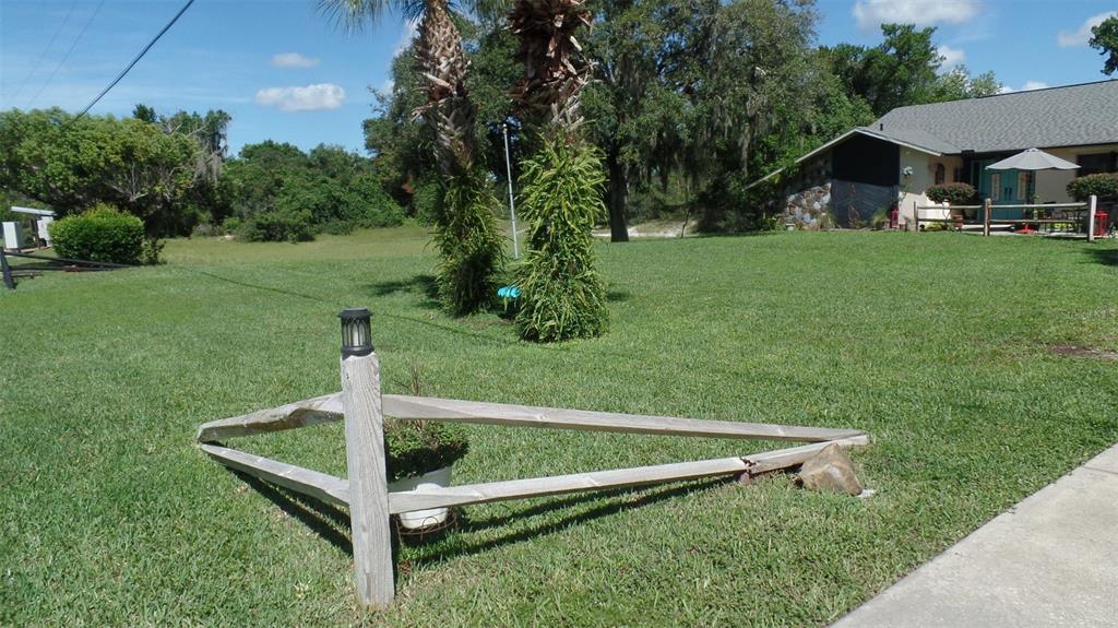 A wooden fence post with a solar light stands in a grassy front yard — 8057 DELAWARE DRIVE, WEEKI WACHEE, FL