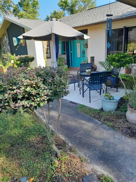 A patio with a table, chairs, and umbrella sits in front of a house entrance — 8057 DELAWARE DRIVE, WEEKI WACHEE, FL