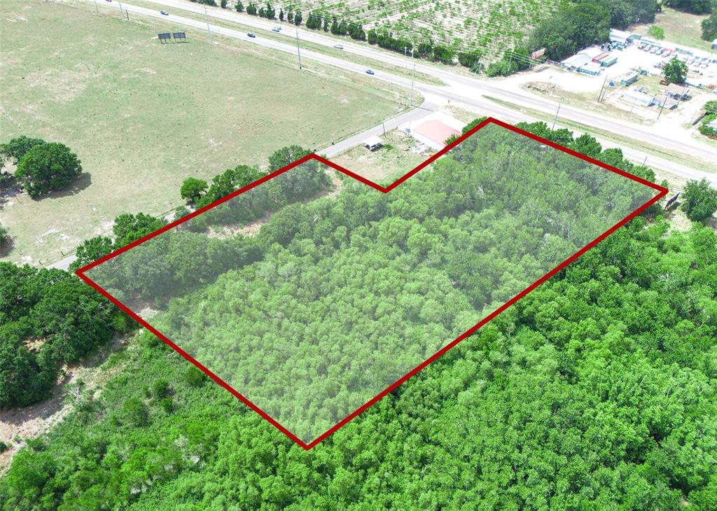 An aerial view shows a wooded, L-shaped plot of land outlined in red near a highway — SR-60, LAKE WALES, FL