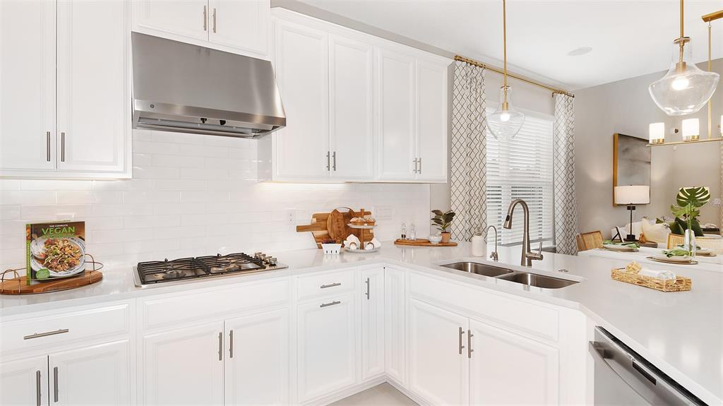 A modern kitchen features white cabinetry, stainless steel appliances, and a light-colored quartz countertop — 32468 SEA LOCH LOOP, MOUNT DORA, FL