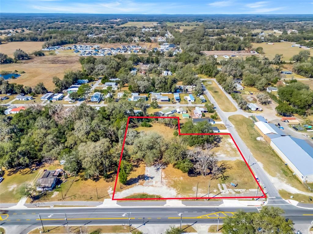 An aerial view shows a vacant, tree-covered lot outlined in red next to existing houses — 82 S MARKET BOULEVARD, WEBSTER, FL