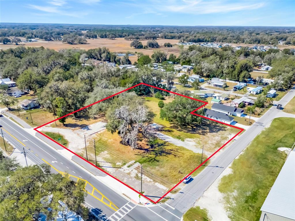 An aerial view shows a vacant lot with trees next to a road and buildings — 82 S MARKET BOULEVARD, WEBSTER, FL