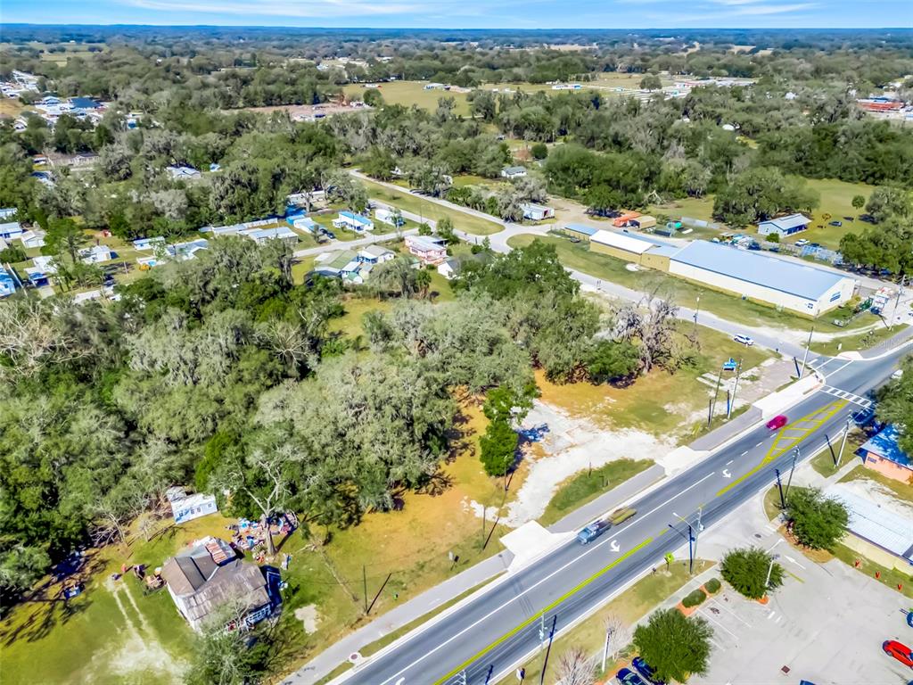 An aerial view shows a vacant lot with trees alongside a road and nearby houses — 82 S MARKET BOULEVARD, WEBSTER, FL