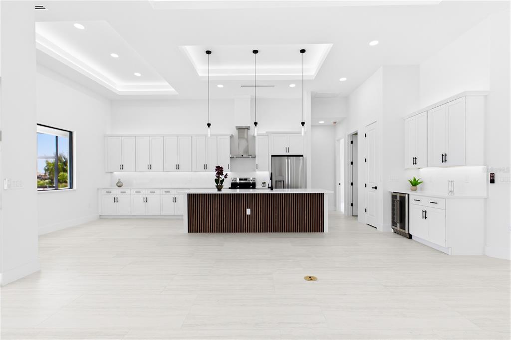 A modern white kitchen features a dark wood-slatted island, stainless steel appliances, and recessed lighting — 2251 SW 2ND TERRACE, CAPE CORAL, FL