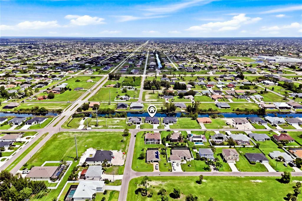 An aerial view shows a suburban neighborhood with houses, canals, and grassy lots — 2251 SW 2ND TERRACE, CAPE CORAL, FL