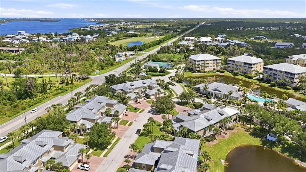 An aerial view shows a residential complex with multiple buildings, a pond, and surrounding greenery — 10600 LEMON CREEK LOOP UNIT 104, ENGLEWOOD, FL