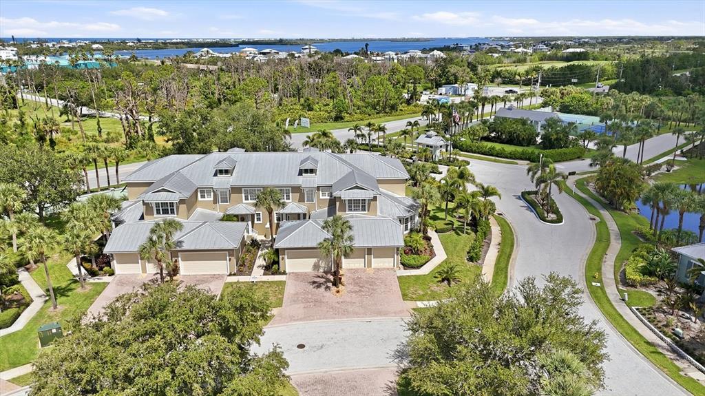 An aerial view shows a multi-unit residential building with a metal roof and paved driveways — 10600 LEMON CREEK LOOP UNIT 104, ENGLEWOOD, FL