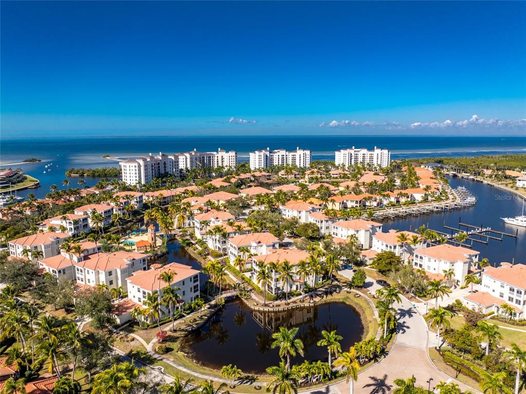 An aerial view of a coastal residential community with multi-story buildings, palm trees, and water — 3464 SUNSET KEY CIRCLE UNIT 103, PUNTA GORDA, FL