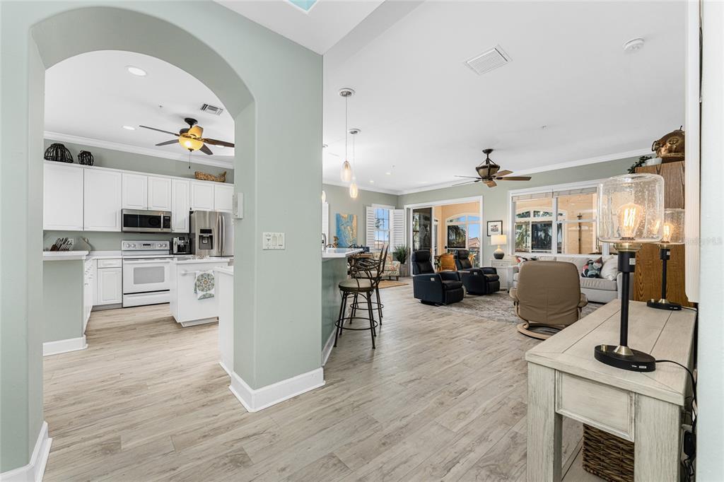An open-concept kitchen and living area with white cabinets, light wood flooring, and ceiling fans — 3464 SUNSET KEY CIRCLE UNIT 103, PUNTA GORDA, FL