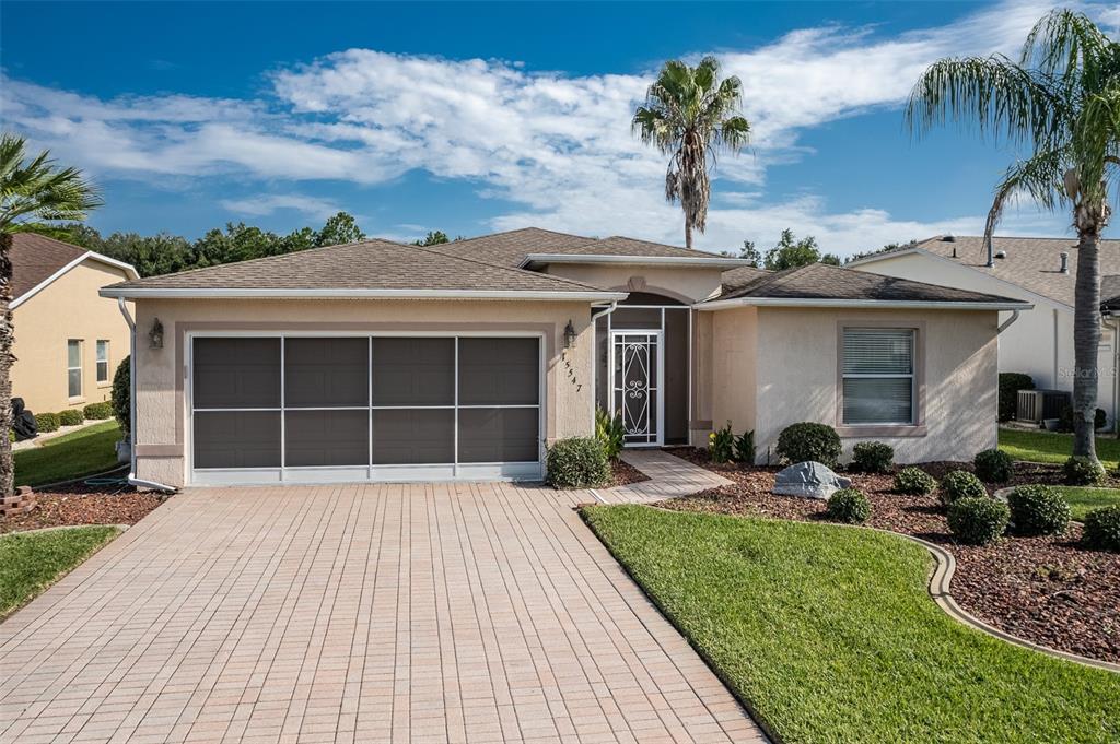 A single-story house with a paved driveway, a screened garage door, and a front entryway — 15547 SW 13TH CIRCLE, OCALA, FL