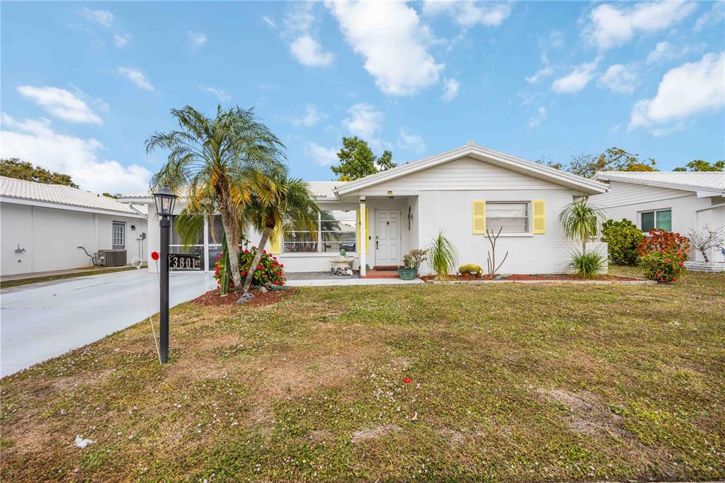 A single-story white house with yellow shutters and a palm tree in the front yard — 3801 CHINABERRY, BRADENTON, FL