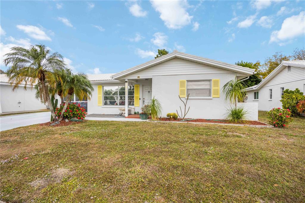 A single-story white house with yellow shutters and a palm tree in the front yard — 3801 CHINABERRY, BRADENTON, FL