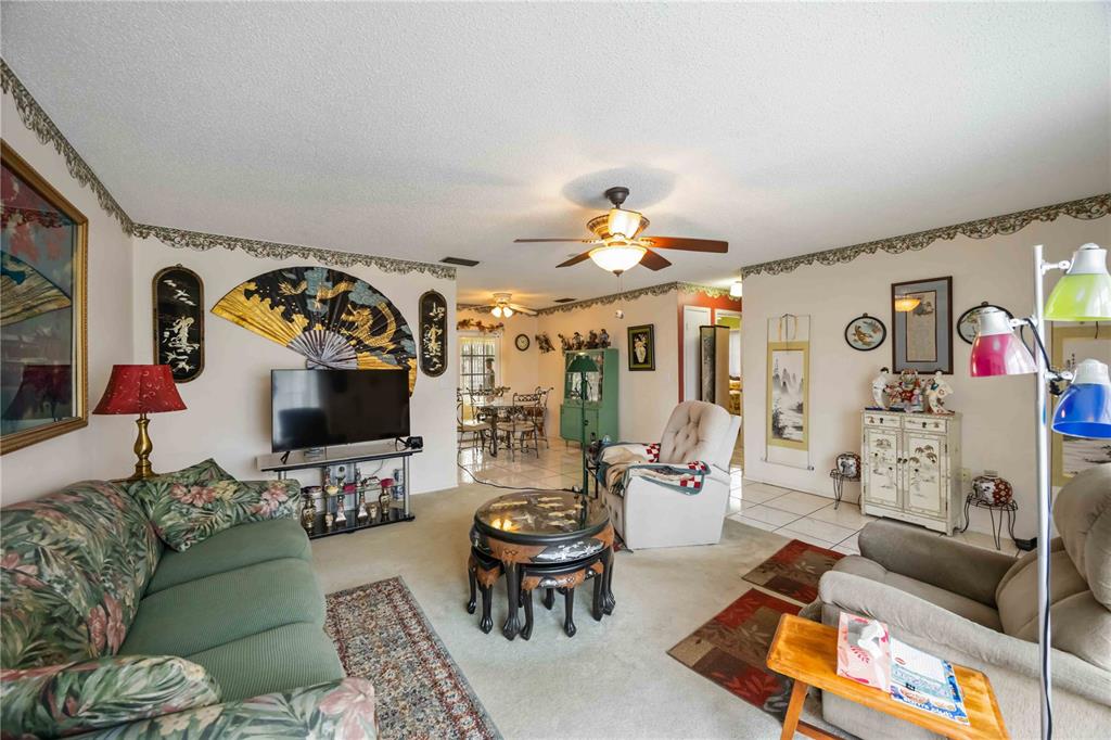 A living room with floral furniture, a ceiling fan, and Asian-inspired decor on the walls — 3801 CHINABERRY, BRADENTON, FL