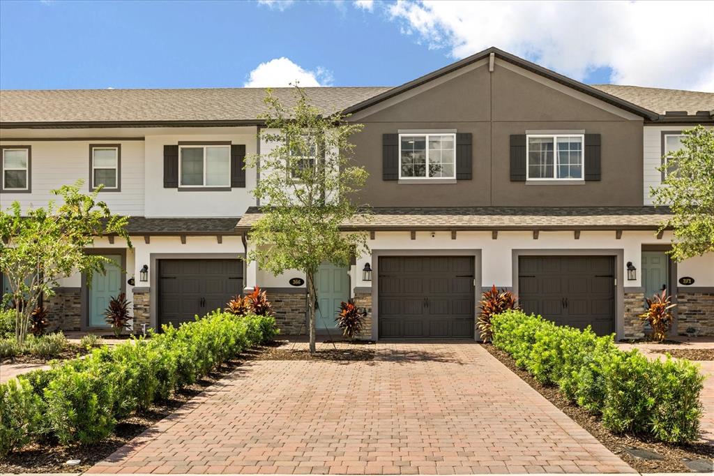 A row of two-story townhomes features brick paver driveways, attached garages, and landscaped front yards — 366 CAPE HONEYSUCKLE PLACE, SANFORD, FL