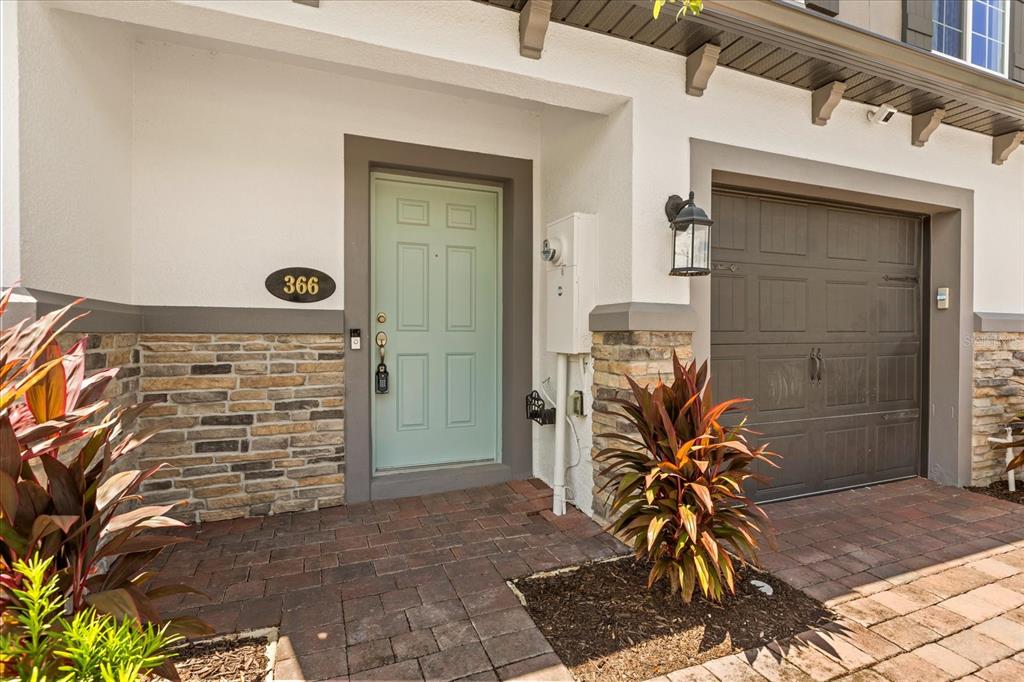 The exterior of a home features a light green front door, stone siding, and a garage — 366 CAPE HONEYSUCKLE PLACE, SANFORD, FL