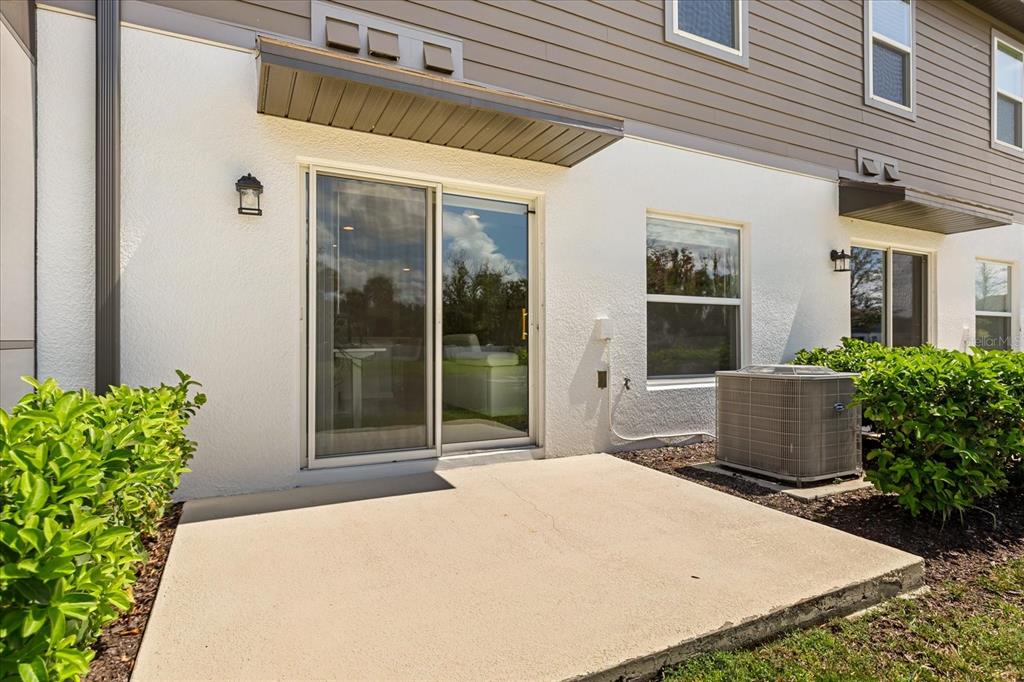 A concrete patio sits outside a sliding glass door with a central air conditioning unit nearby — 366 CAPE HONEYSUCKLE PLACE, SANFORD, FL