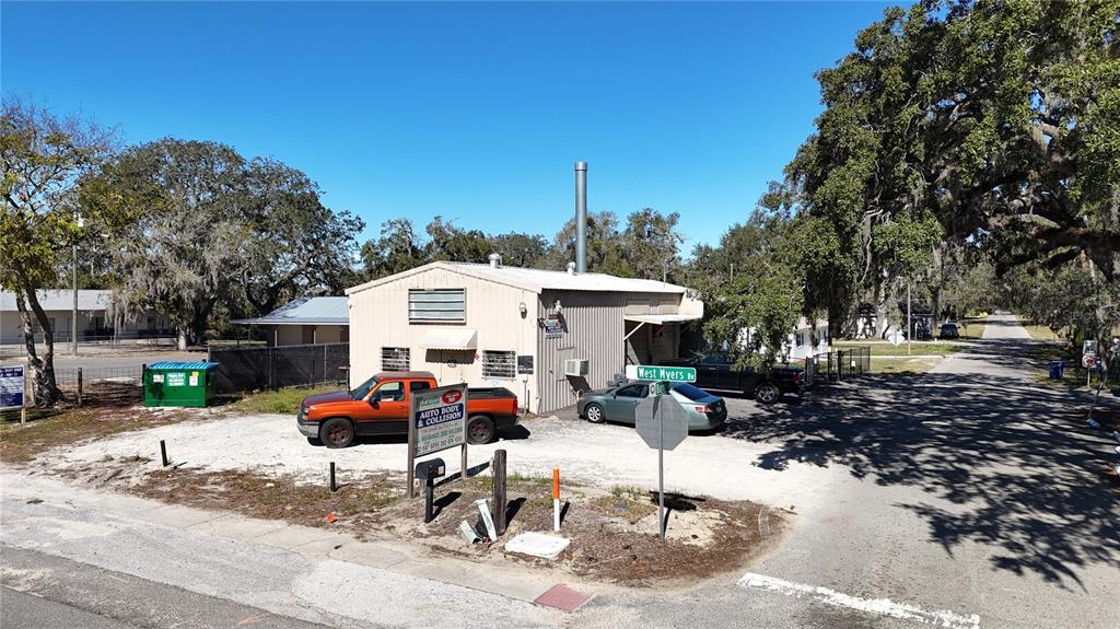 An auto body shop building sits on a gravel lot next to a paved road — 10 BARRY AVENUE, MASCOTTE, FL