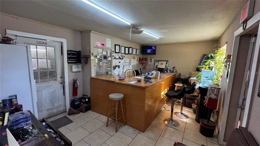 A commercial office space features a wooden service counter, tile flooring, and a glass-paned door — 10 BARRY AVENUE, MASCOTTE, FL