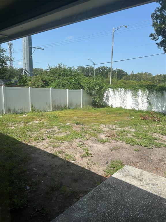 A backyard with patchy grass, a concrete patio, and a white vinyl privacy fence — 3330 LAUREL DALE DRIVE, TAMPA, FL