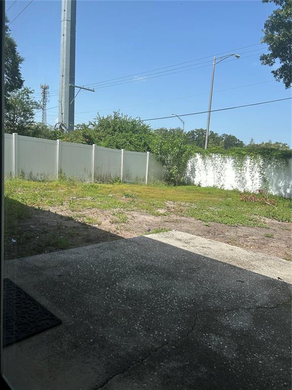 A concrete patio overlooks a grassy backyard enclosed by a white vinyl fence — 3330 LAUREL DALE DRIVE, TAMPA, FL