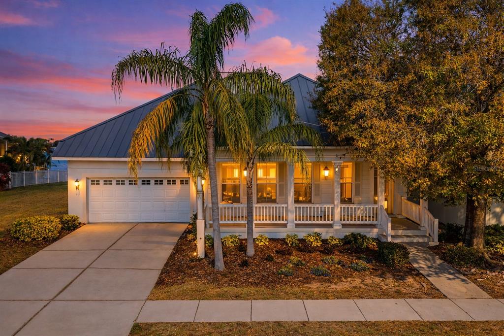 A single-story house with a white exterior, metal roof, front porch, and attached garage — 423 MANNS HARBOR DRIVE, APOLLO BEACH, FL
