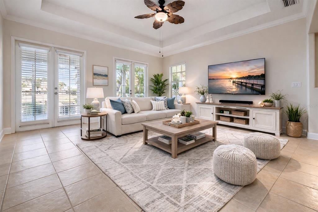 A bright living room features a beige sofa, wooden coffee table, and a wall-mounted television — 423 MANNS HARBOR DRIVE, APOLLO BEACH, FL