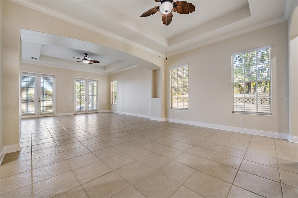 A spacious living area features beige tile flooring, tray ceilings with fans, and large windows — 423 MANNS HARBOR DRIVE, APOLLO BEACH, FL