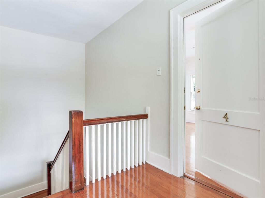 A wooden staircase with white railings leads to a landing with a door labeled four — 2114 W DEKLE AVENUE UNIT 4, TAMPA, FL