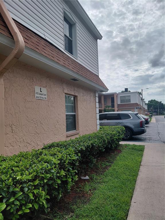 A side view of a two-story apartment building with pink stucco and white siding — 4725 JOSEPH COURT UNIT 229, TAMPA, FL