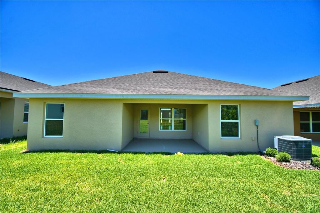 The rear exterior of a single-story house features a covered patio and a grassy yard — 3640 LINDBERGH STREET, LAKELAND, FL